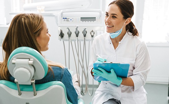 Smiling dentist taking notes on clipboard