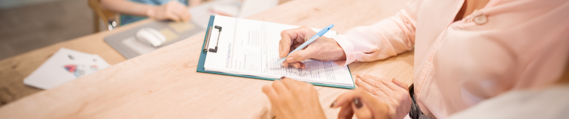 Using a pen to fill out a form on a clipboard