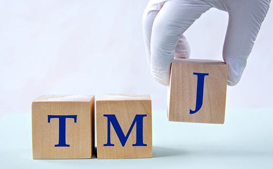 Gloved hand arranging blocks that read “TMJ”