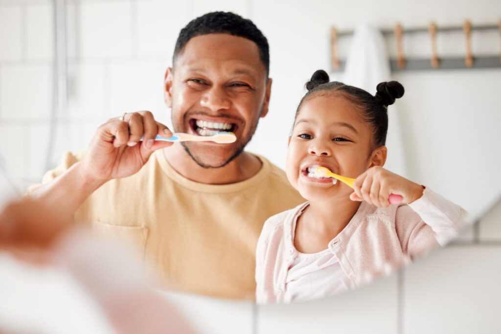 A man and his daughter brushing their teeth