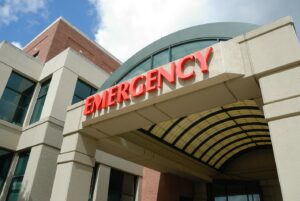 Exterior of emergency room with “emergency” in big red letters.